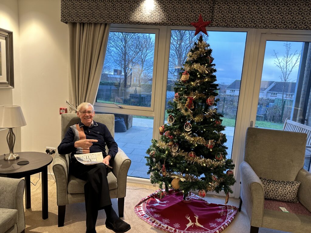 Resident Sitting by Christmas Tree