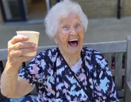 resident smiling holding a cup up