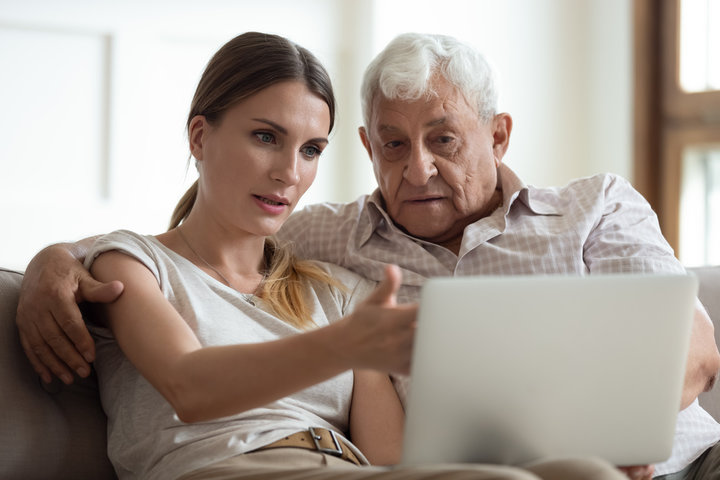 adult daughter helping older father look at care options with laptop